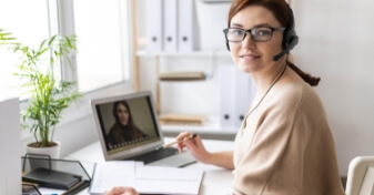 Uma cliente sendo atendida através da videoconferência através de seu notebook em seu escritório