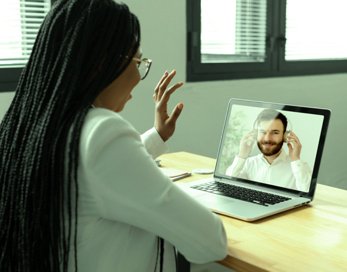 Mulher em sua mesa sendo atendida por videoconferência